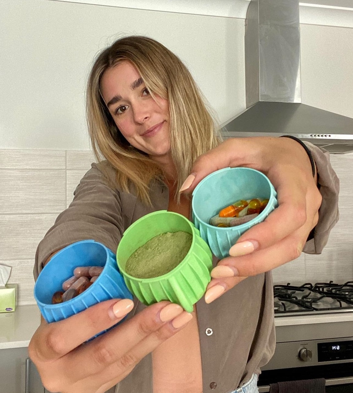 A customer holding three Propod pods filled with greens and vitamins